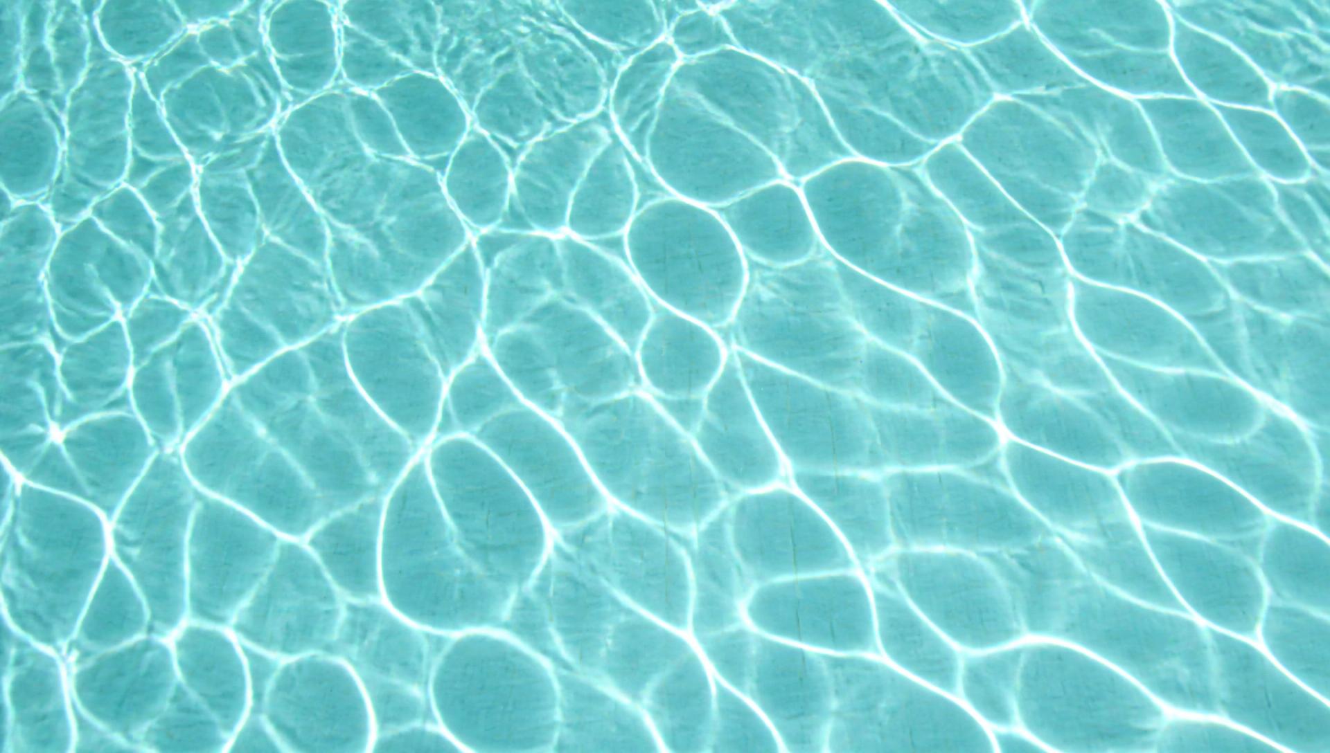 Still water surface with light caustics across pool tile